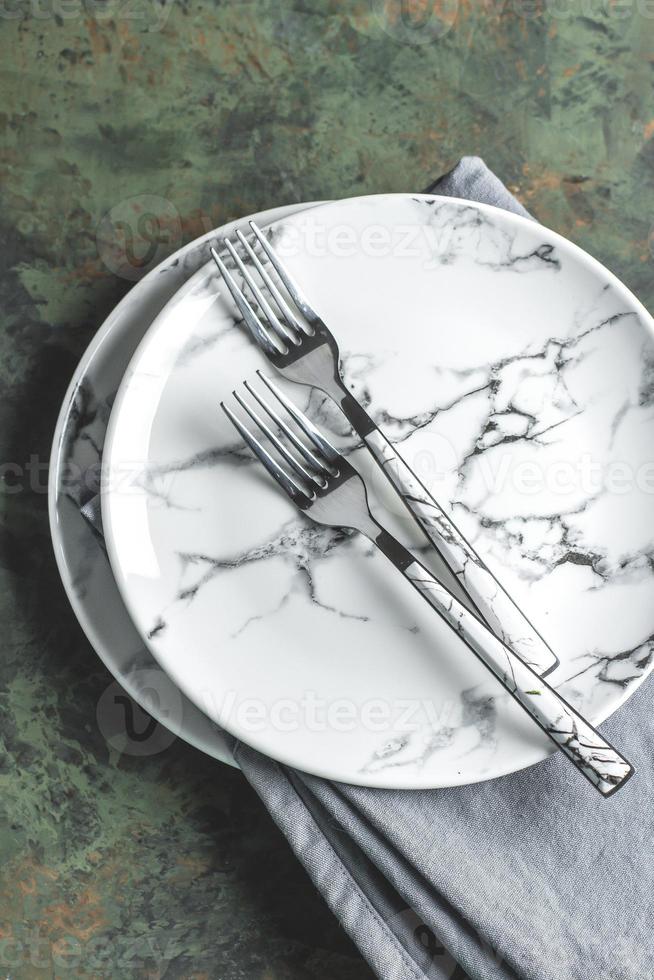 assiette en céramique vide avec fourchette et torchon bleu sur fond de table en béton vert. vue de dessus avec espace de copie. mise à plat. photo