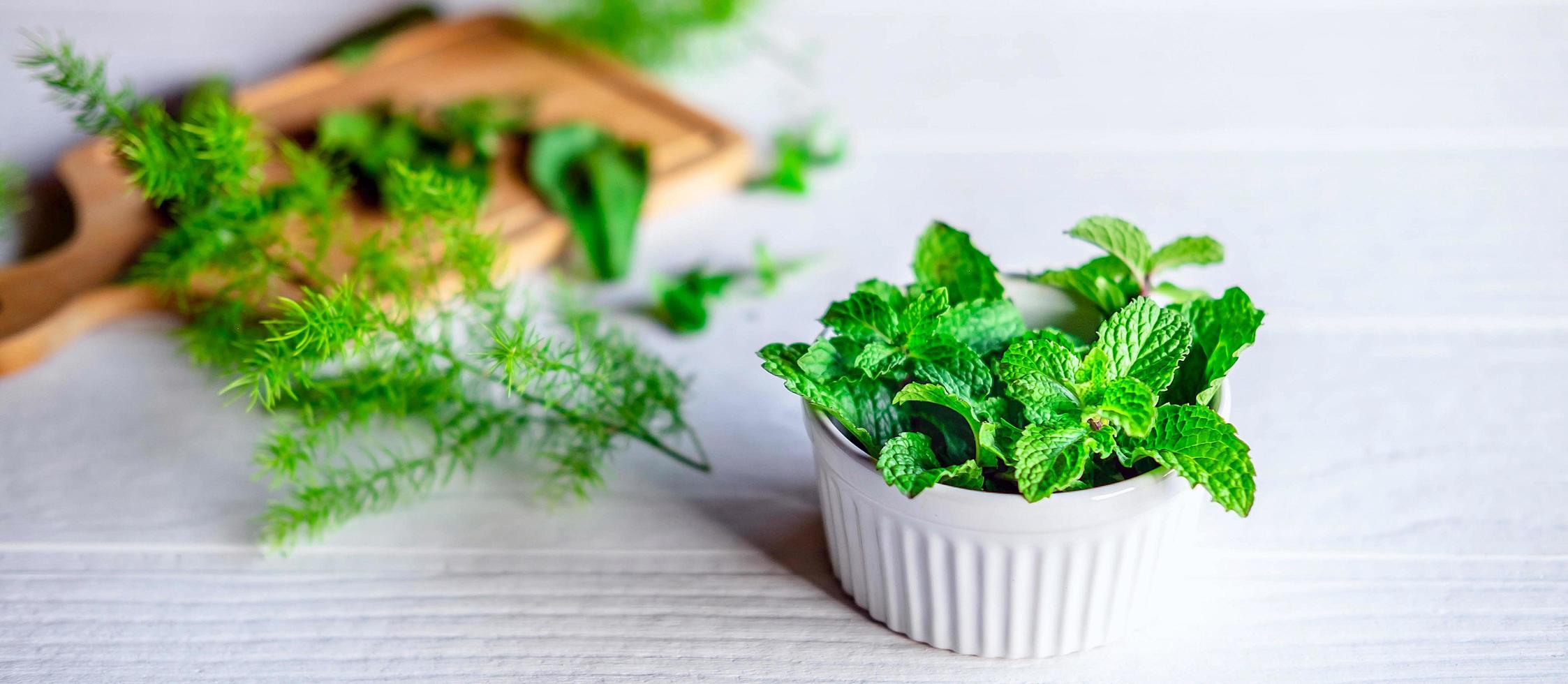 feuille de menthe ou herbes de menthe fraîche dans un bol blanc sur fond blanc photo