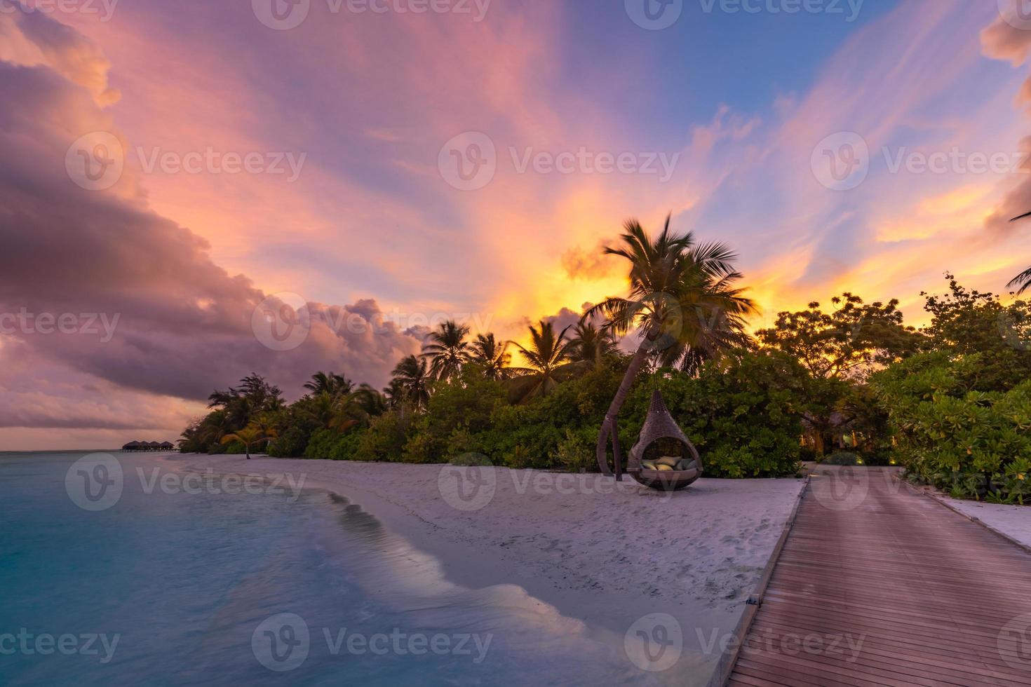 coucher de soleil sur l'île des maldives, complexe de villas de luxe sur l'eau et jetée en bois. beau ciel et nuages et fond de plage pour les vacances d'été et le concept de voyage. paysage de coucher de soleil paradisiaque photo