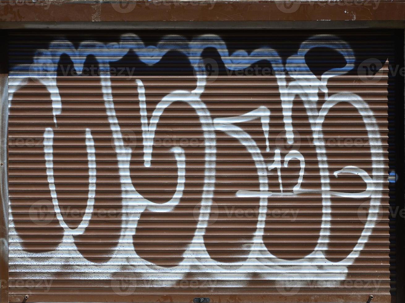 fragment d'un ancien dessin de graffitis colorés sur la porte de l'obturateur. image d'arrière-plan illustrant l'art de la rue, le vandalisme et la peinture murale avec de la peinture aérosol photo