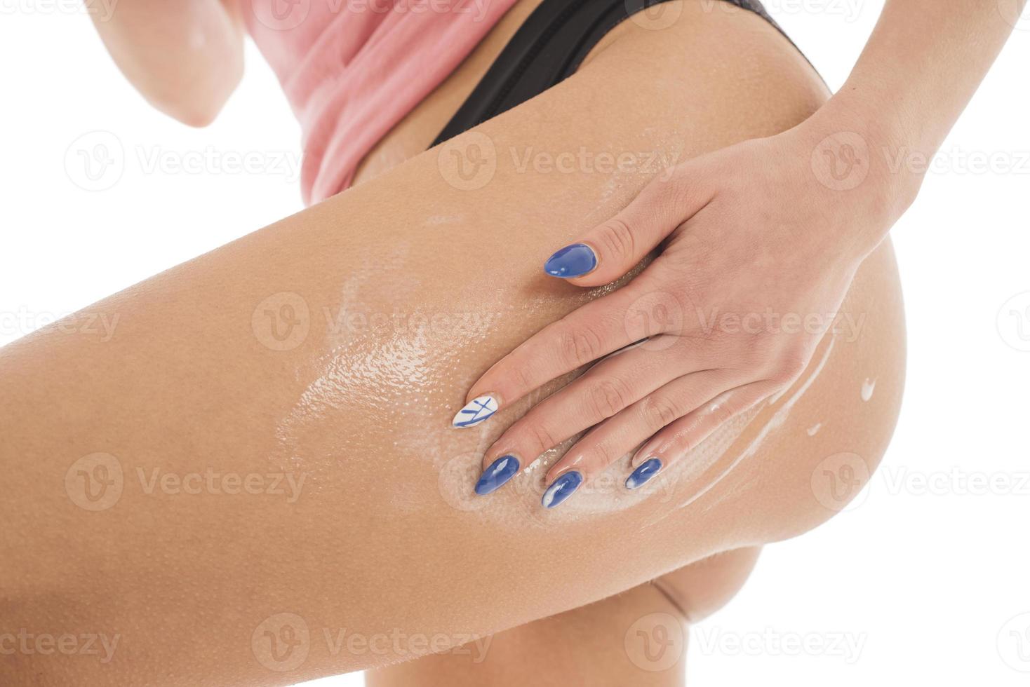 la femme applique une lotion pour le corps sur ses jambes. isolé sur fond blanc photo