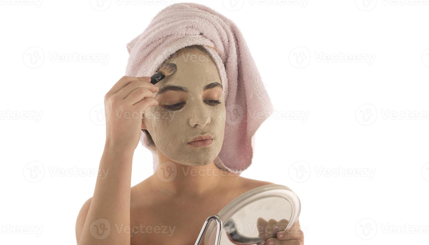 procédures de beauté concept de soins de la peau. jeune femme appliquant un masque d'argile de boue faciale sur son visage photo