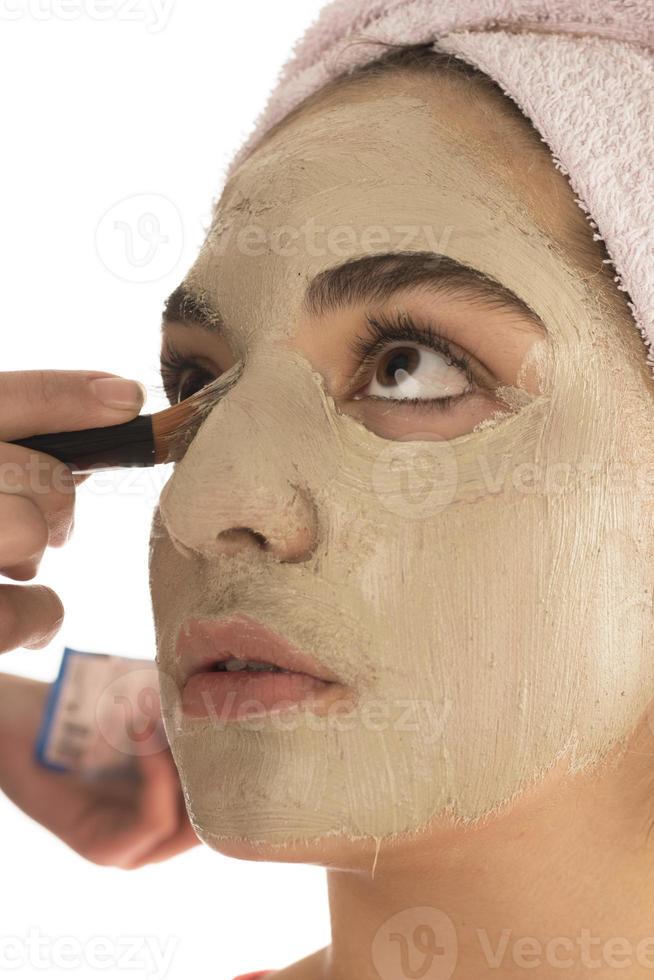 procédures de beauté concept de soins de la peau. jeune femme appliquant un masque d'argile de boue faciale sur son visage photo
