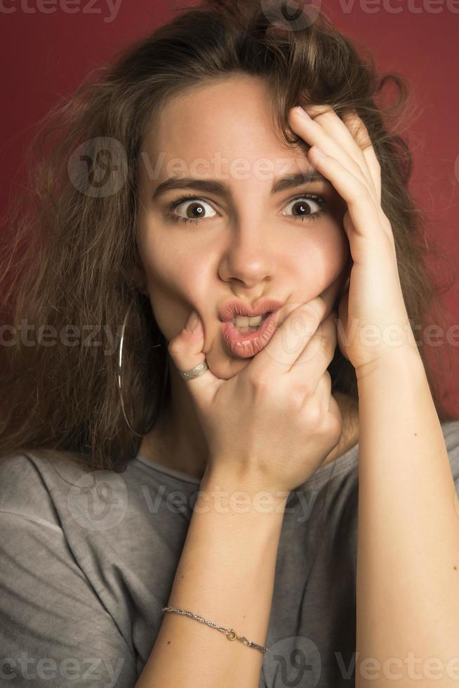 portrait d'une adolescente européenne positive émotionnelle portant ses cheveux clairs en chignon, criant d'étonnement ou d'étonnement en gardant les mains sur le visage photo