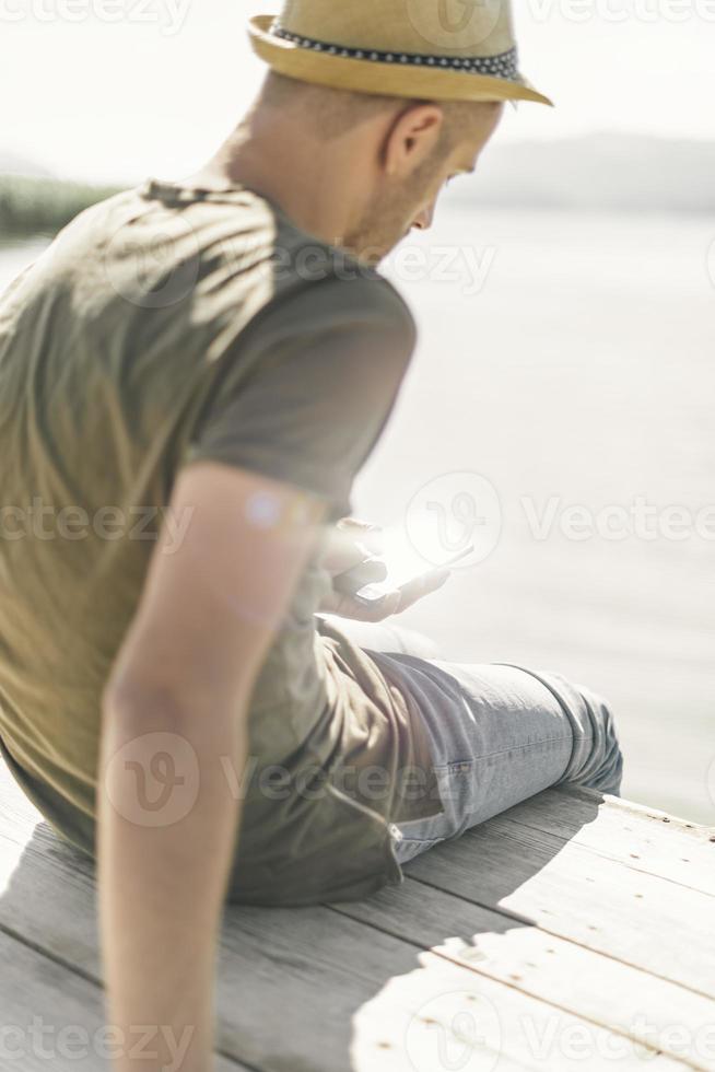 jeune homme sur poire au bord d'un lac lors d'une journée ensoleillée de détente. photo