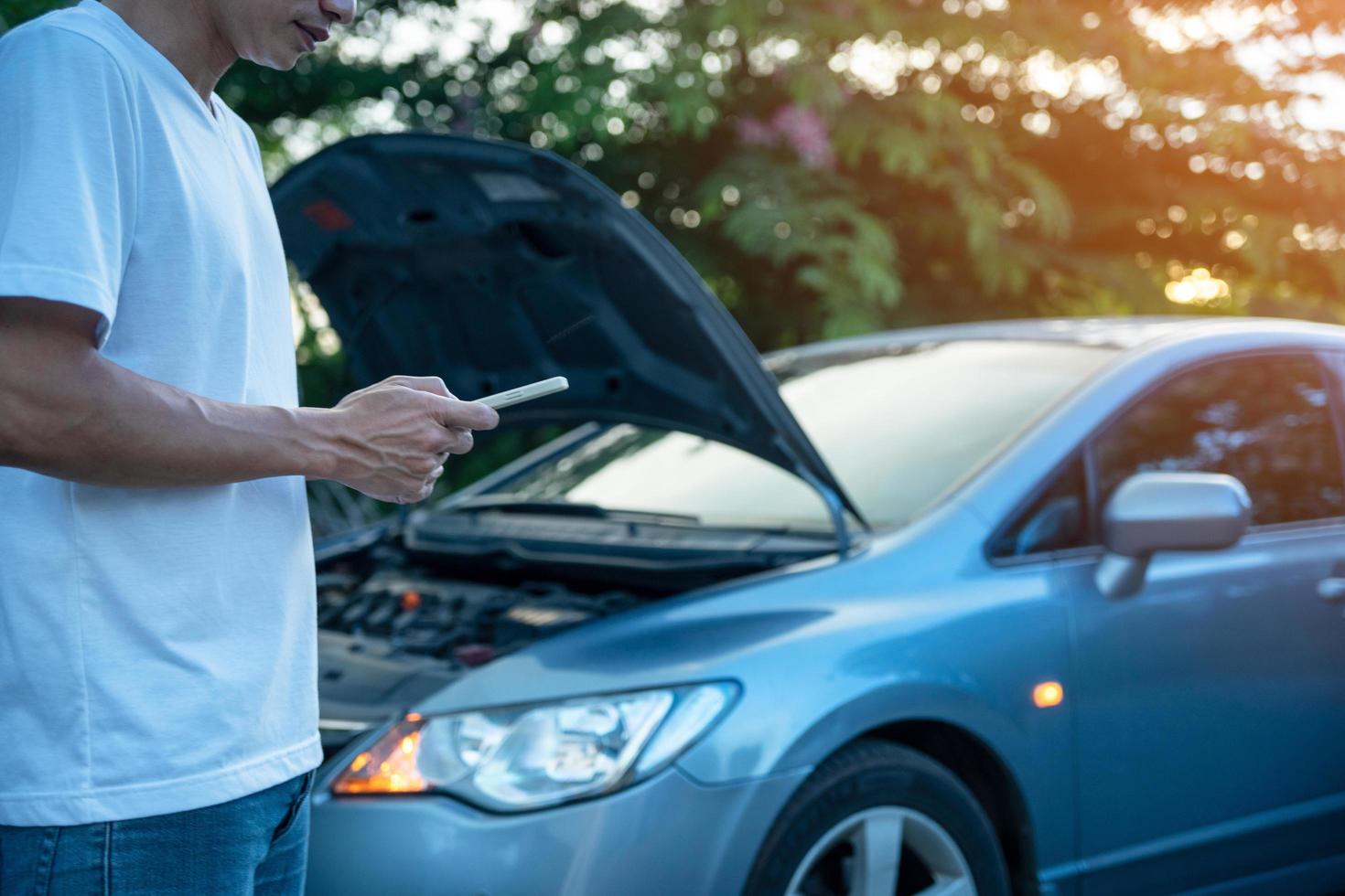 sécurité d'urgence. l'homme utilise le téléphone pour appeler un mécanicien parce que sa voiture tombe en panne. assurance automobile et assurance accident pendant le voyage photo