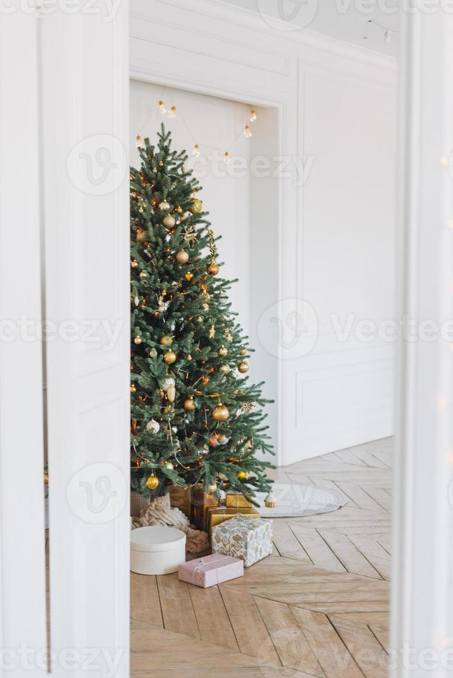 arbre de noël décoré dans des jouets dorés et blancs avec les coffrets cadeaux de la porte à l'intérieur lumineux, fond texturé photo