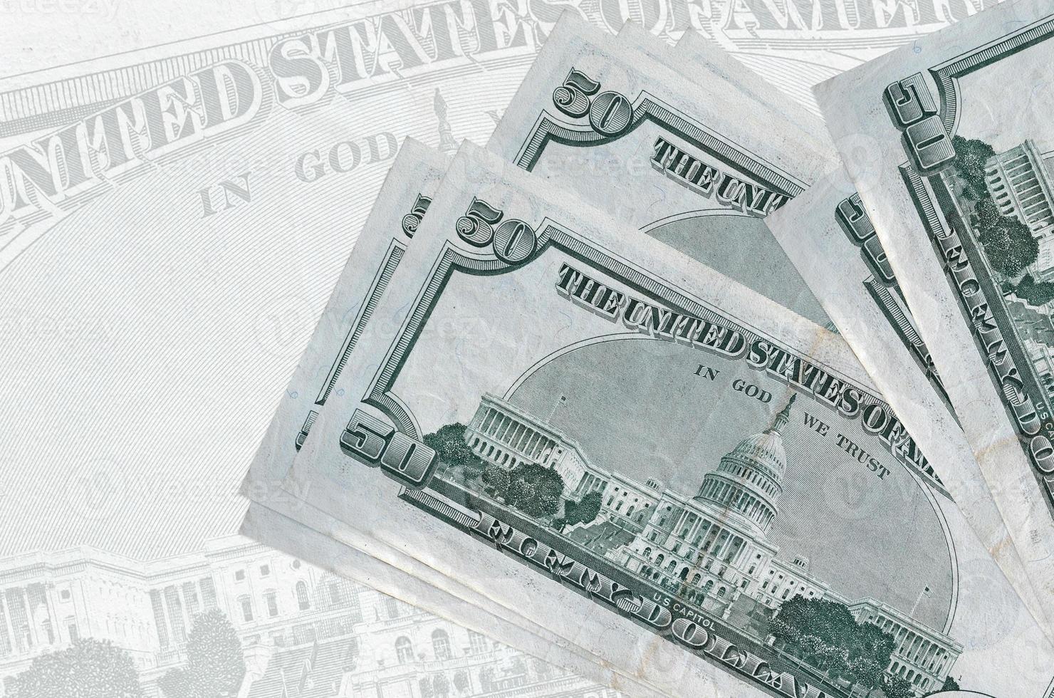 Des billets de 50 dollars américains sont empilés sur fond de gros billets de banque semi-transparents. présentation abstraite de la monnaie nationale photo