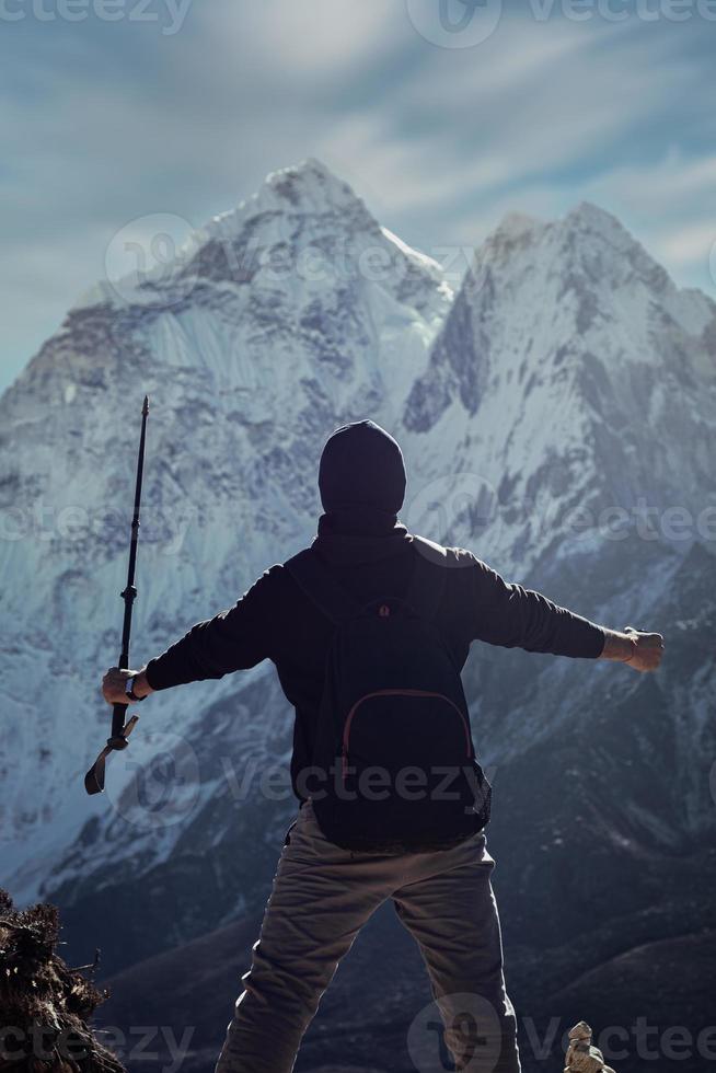 une silhouette d'un homme au népal surplombe la montagne ama dablam dans le village de dingboche dans le ciel bleu et nuageux avec une grande montagne enneigée. photo