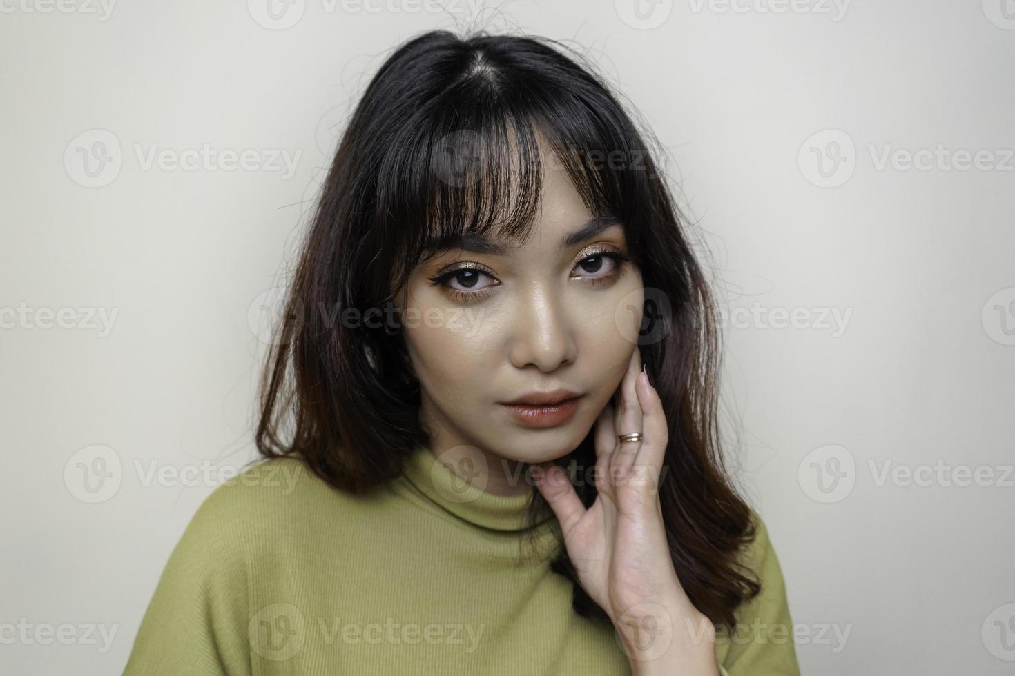 un visage joyeux de beauté de jeune mannequin asiatique portant un haut vert. soin du visage beauté soins de la peau, spa, concept de santé féminine. photo