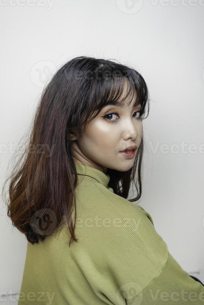 un visage joyeux de beauté de jeune mannequin asiatique portant un haut vert. soin du visage beauté soins de la peau, spa, concept de santé féminine. photo