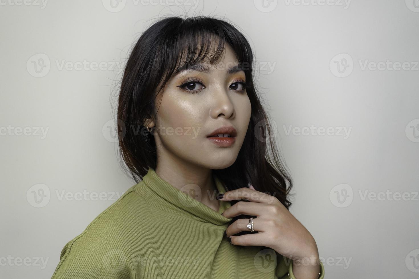 un visage joyeux de beauté de jeune mannequin asiatique portant un haut vert. soin du visage beauté soins de la peau, spa, concept de santé féminine. photo