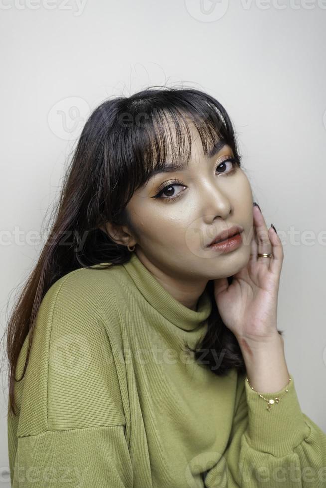 un visage joyeux de beauté de jeune mannequin asiatique portant un haut vert. soin du visage beauté soins de la peau, spa, concept de santé féminine. photo