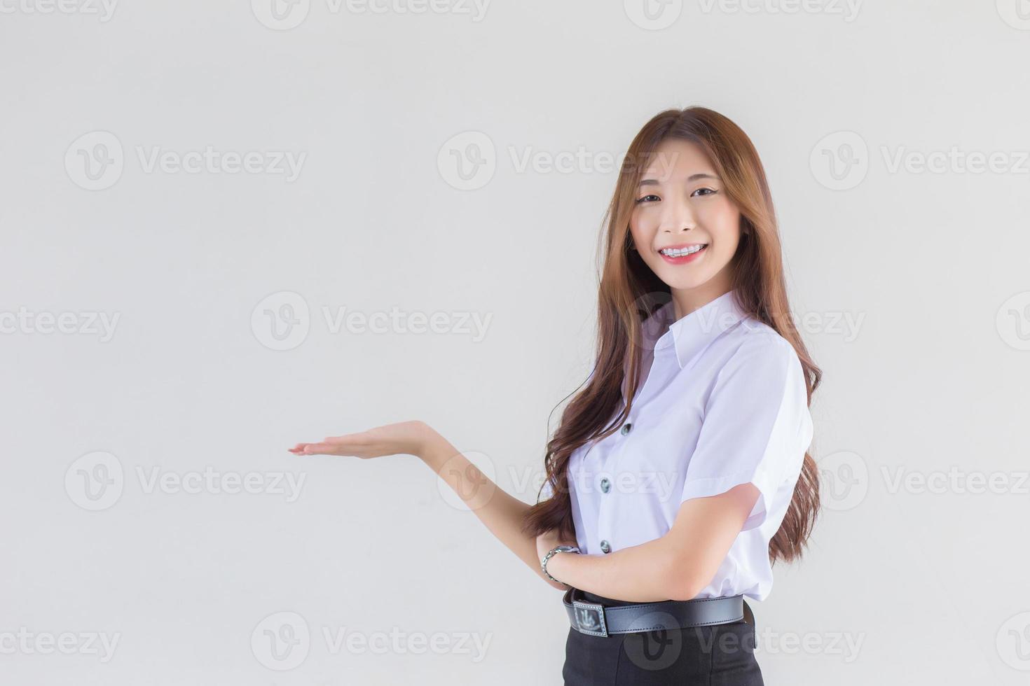 portrait d'un étudiant thaïlandais adulte en uniforme d'étudiant universitaire. belle fille asiatique debout pour présenter quelque chose en toute confiance sur fond blanc. photo