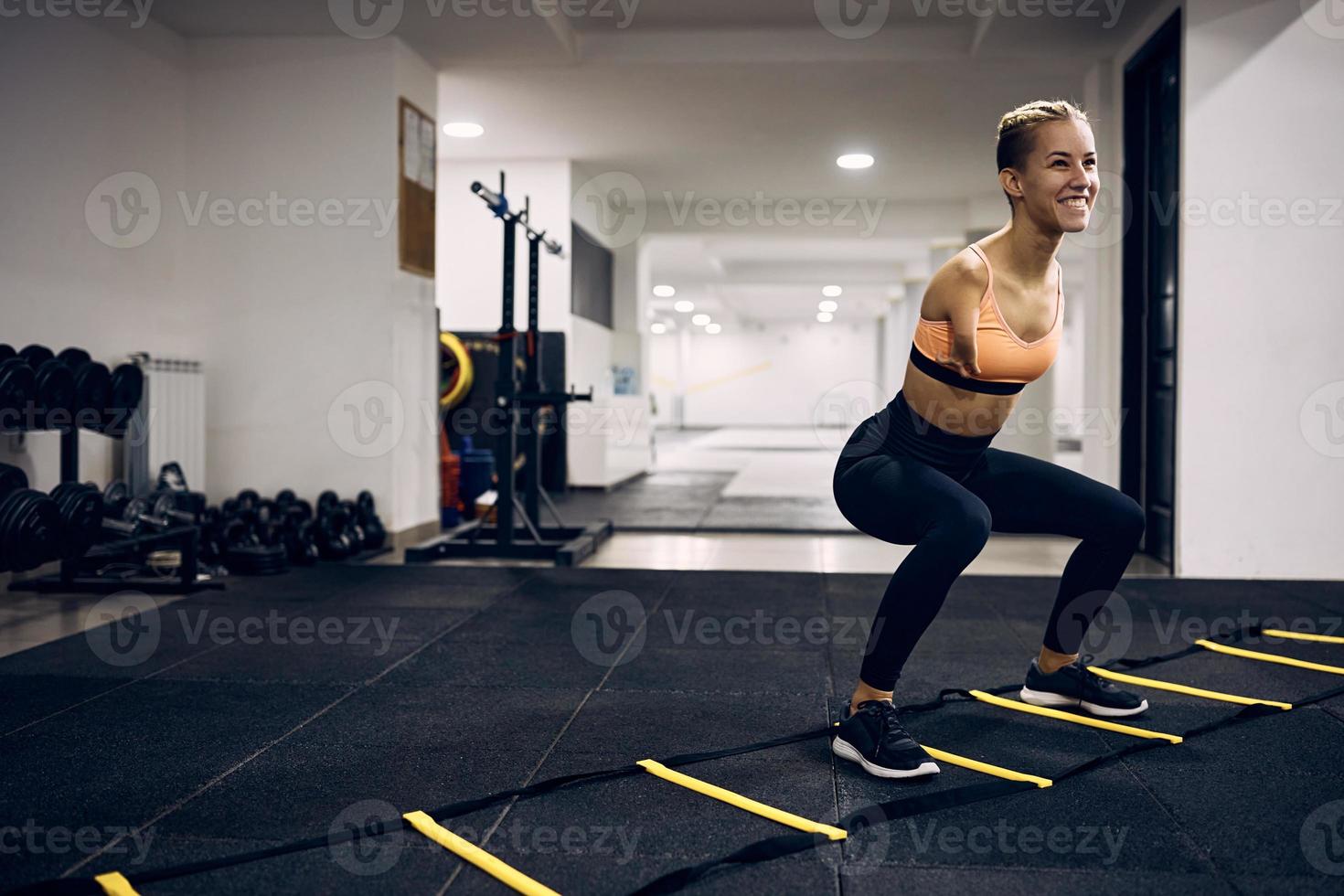 Heureuse sportive handicapée faisant de l'exercice avec une échelle d'agilité des pieds dans une salle de sport. photo