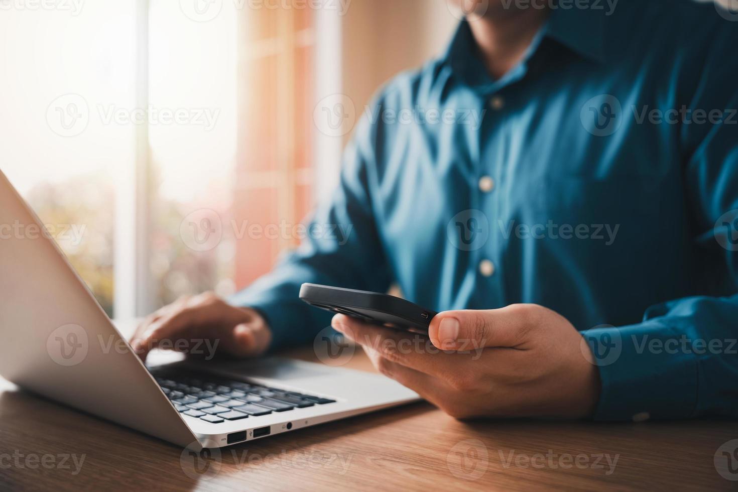 un homme d'affaires travaillant à l'aide de téléphones portables et d'ordinateurs portables assure la liaison avec les clients et planifie des stratégies commerciales, en travaillant des concepts utilisant la technologie de la manière la plus efficace. photo