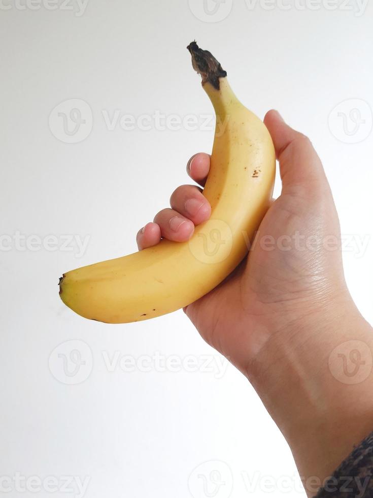 photo blanche isolée de la main d'une femme tenant une banane jaune cavendish.