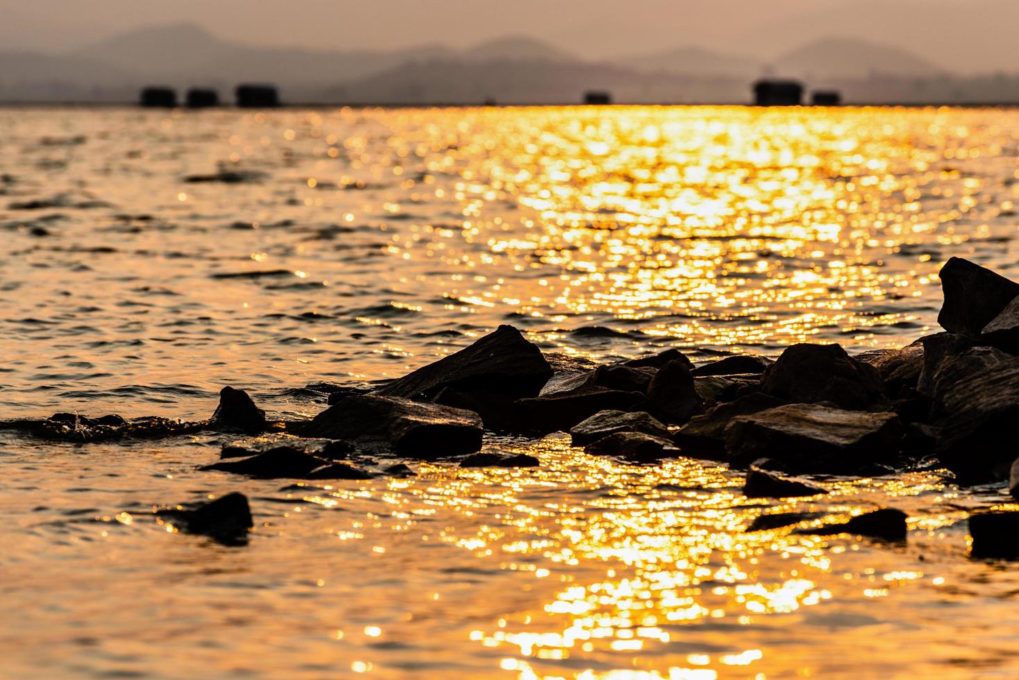 rocher dans l'eau la lumière du soleil reflète la lueur jaune photo