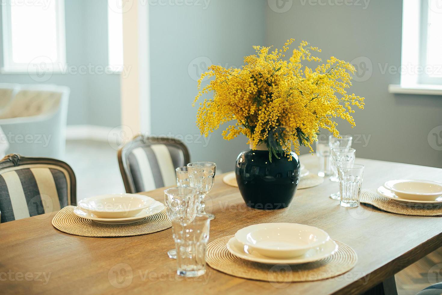 table en bois avec assiettes et verres vides. table de fête de pâques. branches de mimosa dans un vase photo