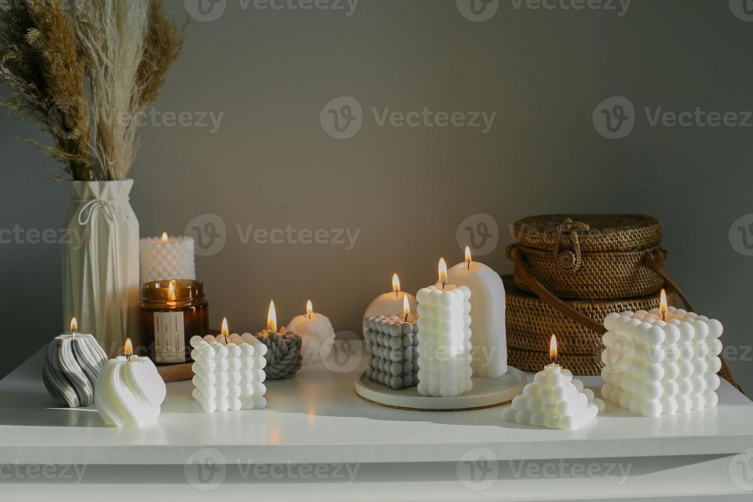 décoration intérieure de la maison. commode blanche avec fleurs séchées dans un vase, sacs en rotin et bougies variées. nature morte, concept hygge photo