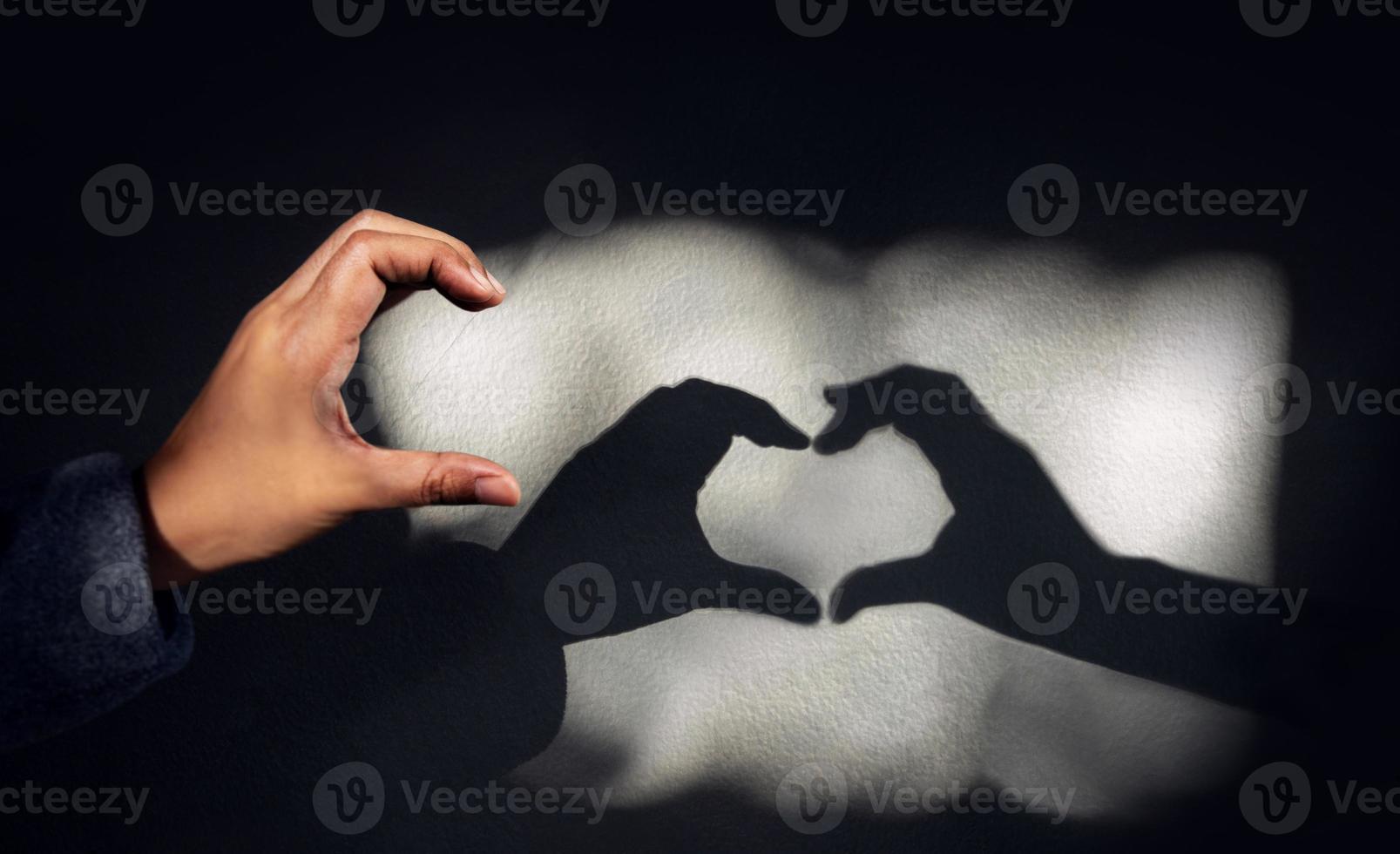 photo conceptuelle pour l'amour et la relation. personne de solitude utilisant la main de geste pour former une ombre en forme de coeur sur le mur. j'espère correspondre à quelqu'un