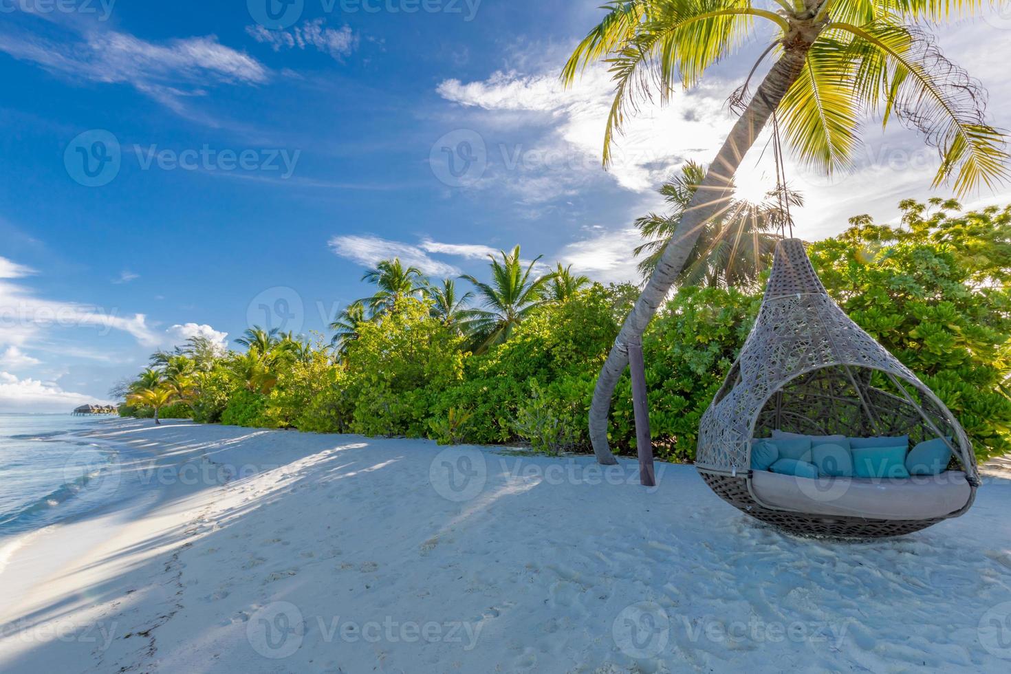 belle plage tropicale des maldives sous un ciel nuageux avec balançoires ou hamac sur cocotier. concept de vacances de luxe. paysage de voyage, côte nature. plage paisible, vue ensoleillée sur île paradisiaque photo