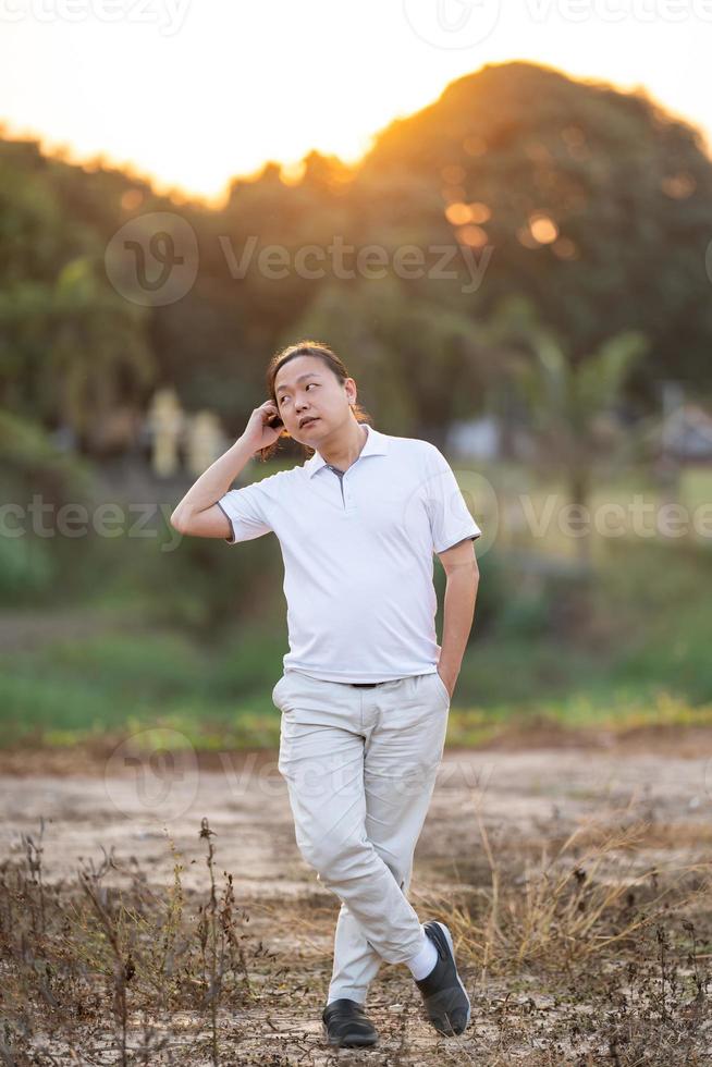 les cheveux longs d'un homme asiatique se dressent et se détendent sur le terrain sec au crépuscule doré. photo