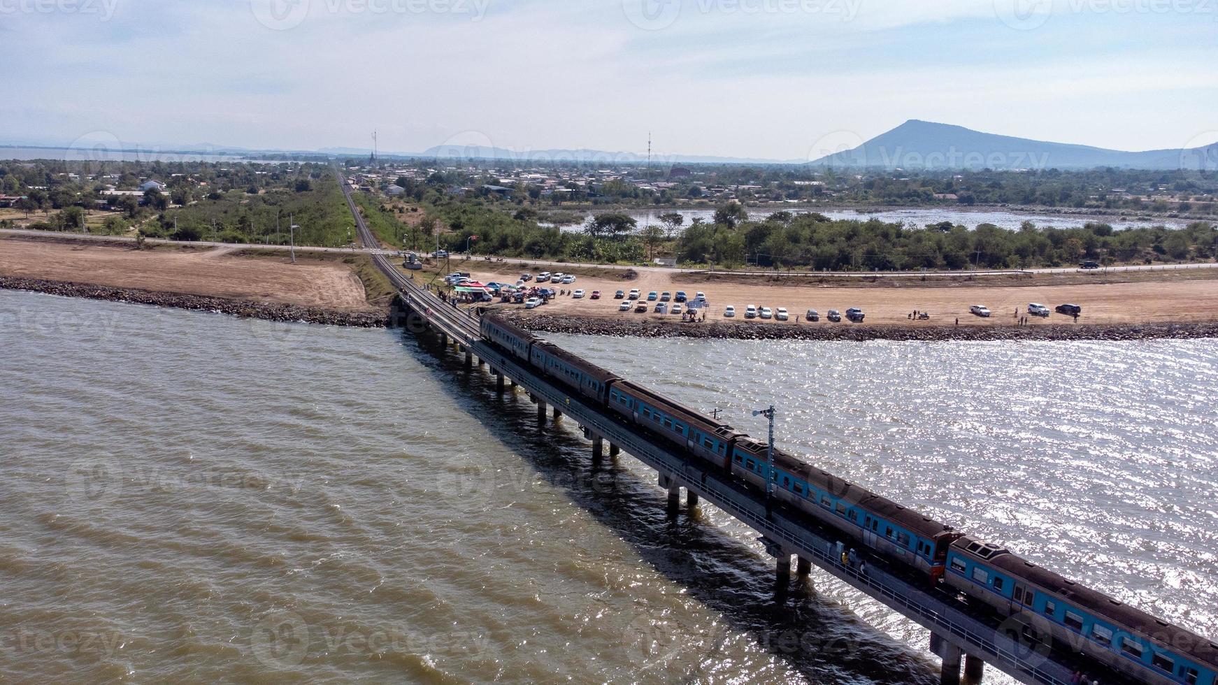 vue aérienne d'un incroyable train de voyage garé sur un pont ferroviaire flottant au-dessus de l'eau du lac dans le barrage de pa sak jolasid avec un ciel bleu à lopburi, en thaïlande. photo