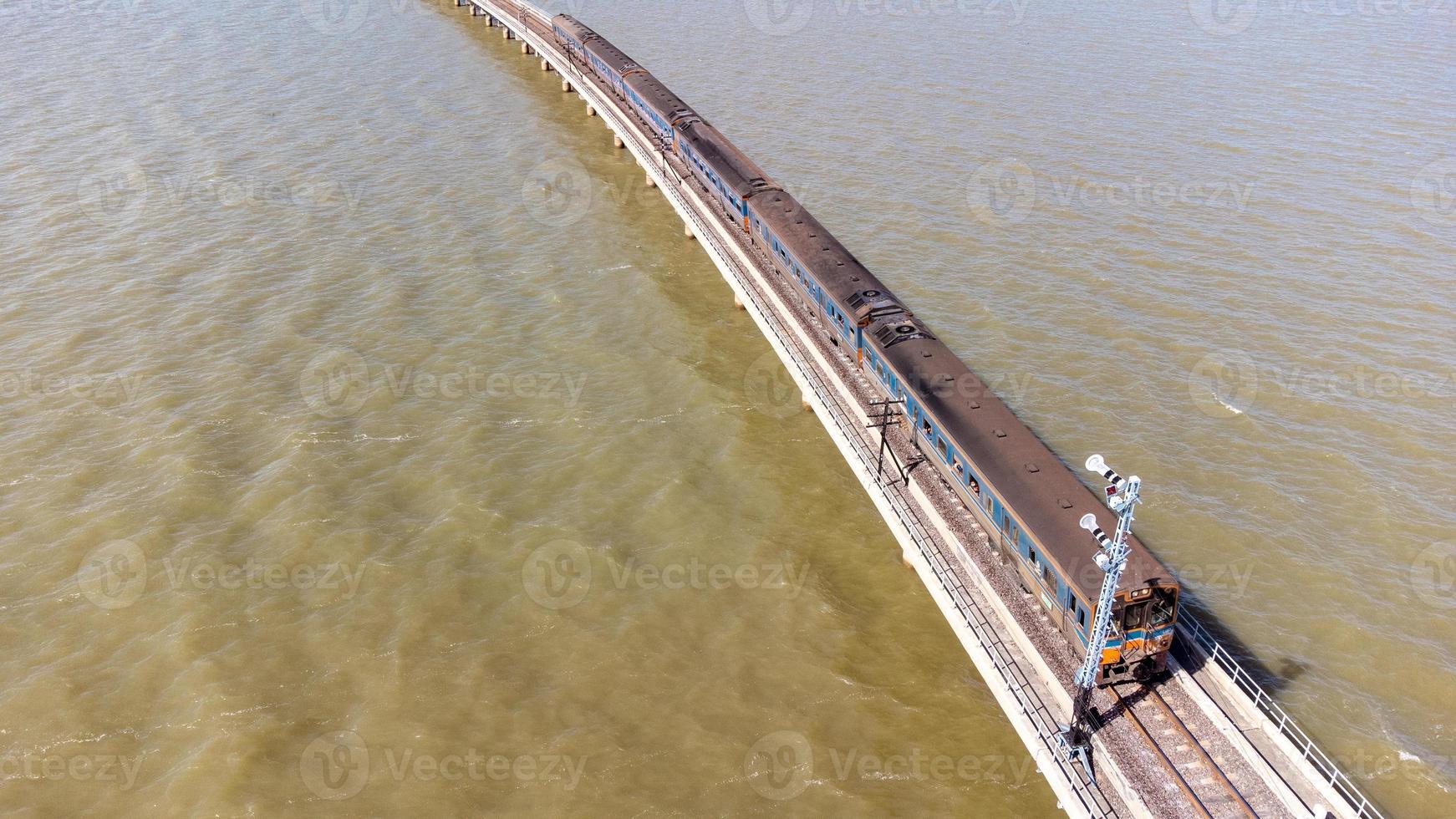 vue aérienne d'un incroyable train de voyage garé sur un pont ferroviaire flottant au-dessus de l'eau du lac dans le barrage de pa sak jolasid avec un ciel bleu à lopburi, en thaïlande. photo