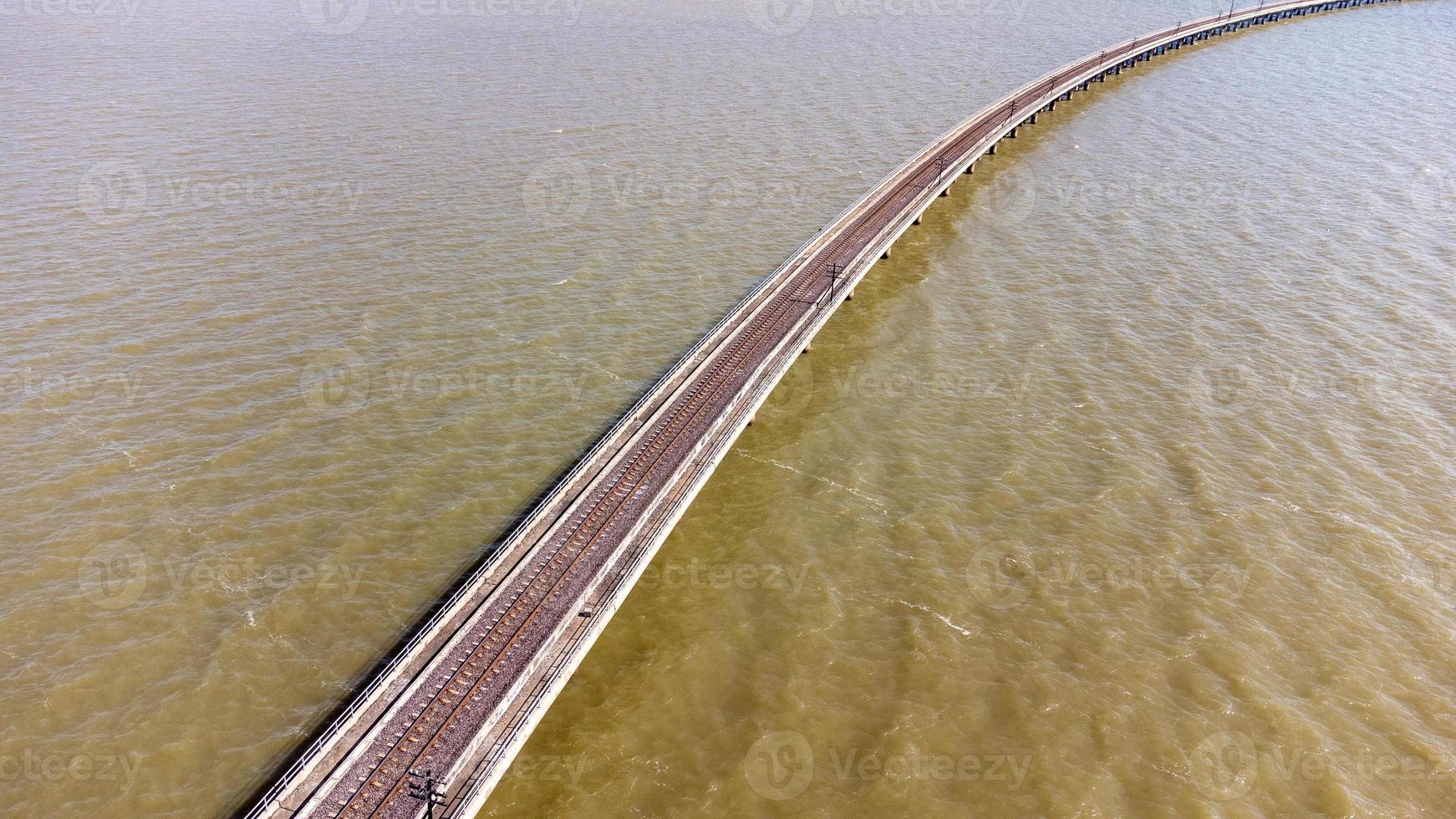 vue aérienne d'un incroyable train de voyage garé sur un pont ferroviaire flottant au-dessus de l'eau du lac dans le barrage de pa sak jolasid avec un ciel bleu à lopburi, en thaïlande. photo