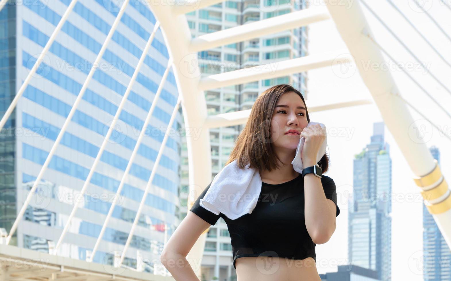 jeune femme sportive en vêtements de sport debout et essuyant la sueur après avoir couru ou fait de l'exercice en ville photo