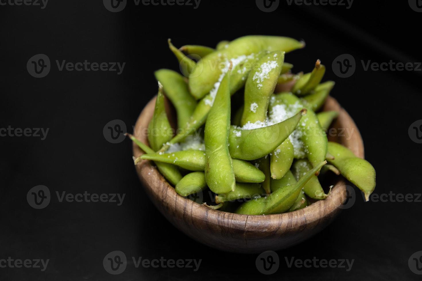 salade de haricots edamame au sel de mer servie dans un bol sombre. isolé sur fond noir. nourriture de restaurant. cuisine japonaise photo