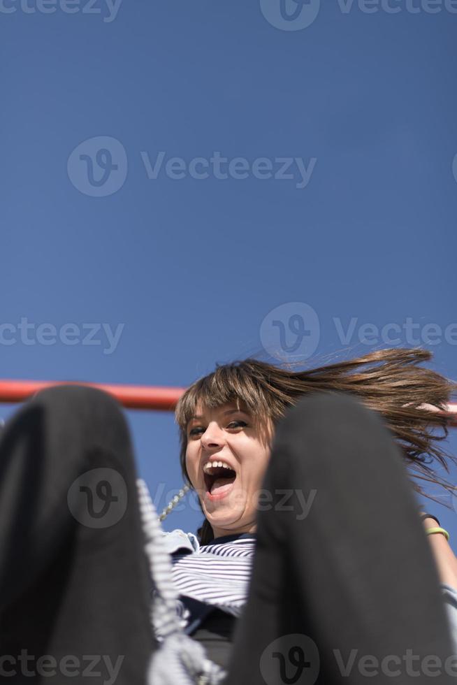 une femme infantile et heureuse assise sur un toboggan pour enfants sur une aire de jeux photo