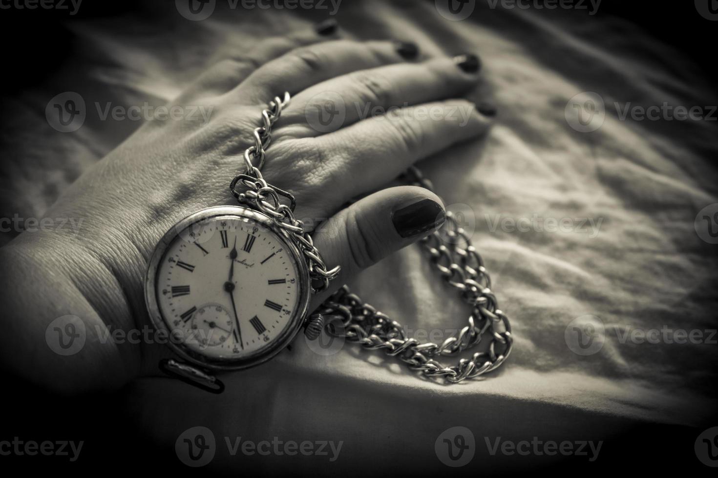 un gros plan de la main d'une femme tenant une montre rétro en noir et blanc photo
