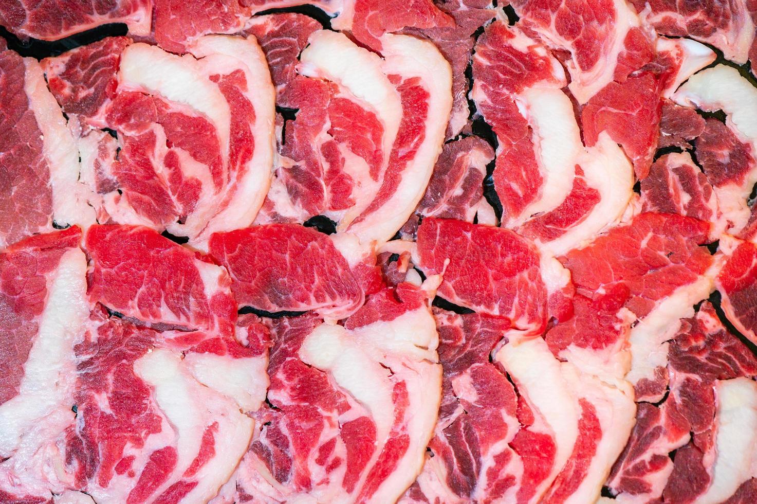 faites glisser du boeuf cru pour yakiniku. mince morceau de boeuf pour shabu hotpot style de cuisine japonaise. gros plan sur un œil de mandrin de viande fraîche pour sukiyaki. vue de dessus photo