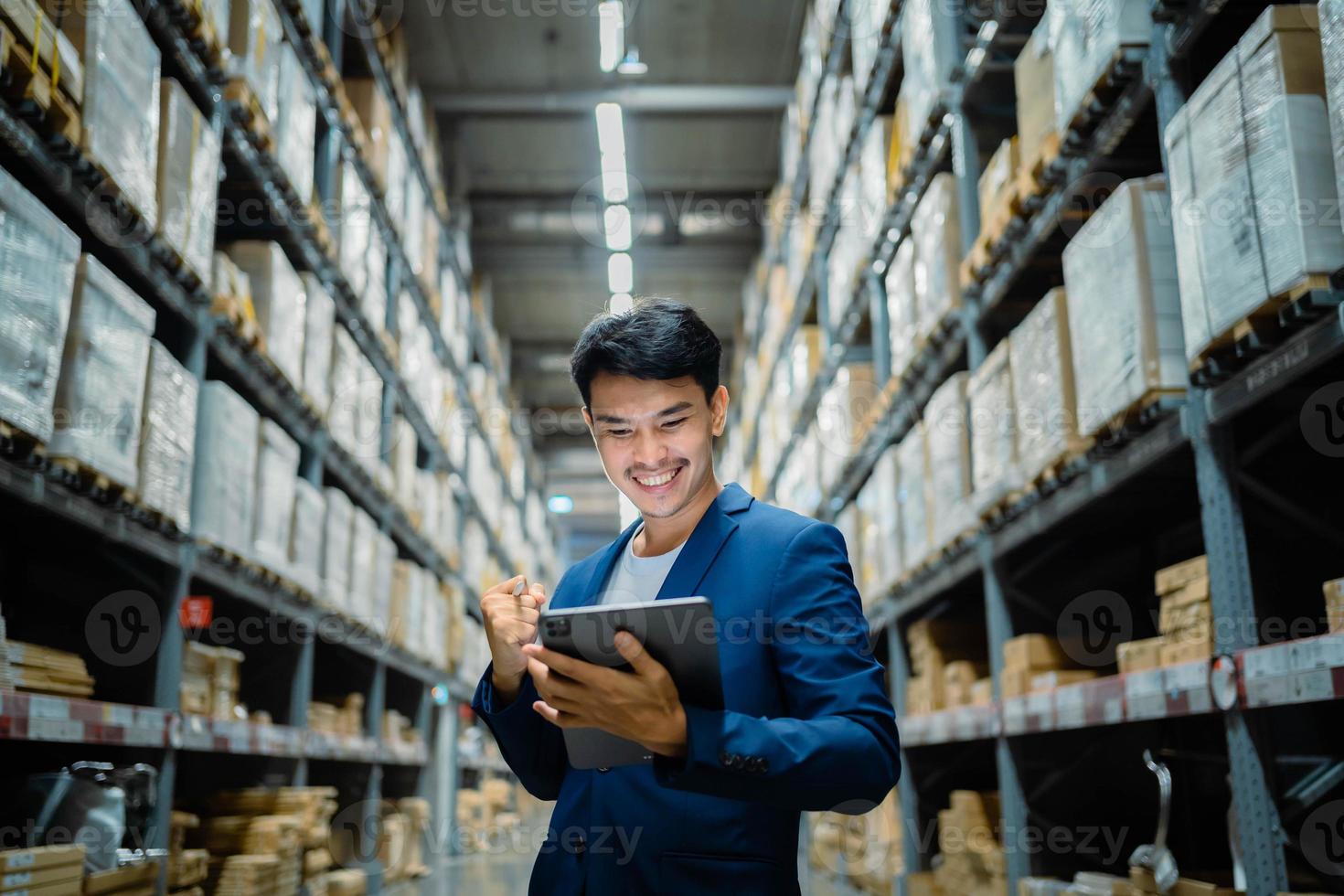 Succès. un homme d'affaires asiatique dans un grand entrepôt vérifie les boîtes en carton dans un centre de distribution logistique. Logistique et entrepôt d'usine d'exportation. industriel d'entreprise. entrepôt photo