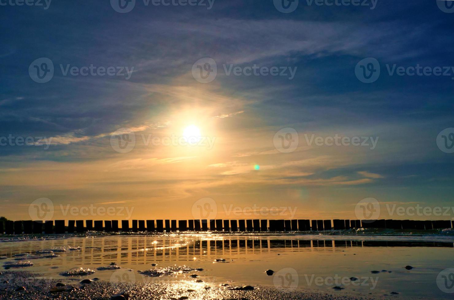 les épis s'avancent dans la mer au coucher du soleil. le soleil brille sur la mer baltique. paysage photo