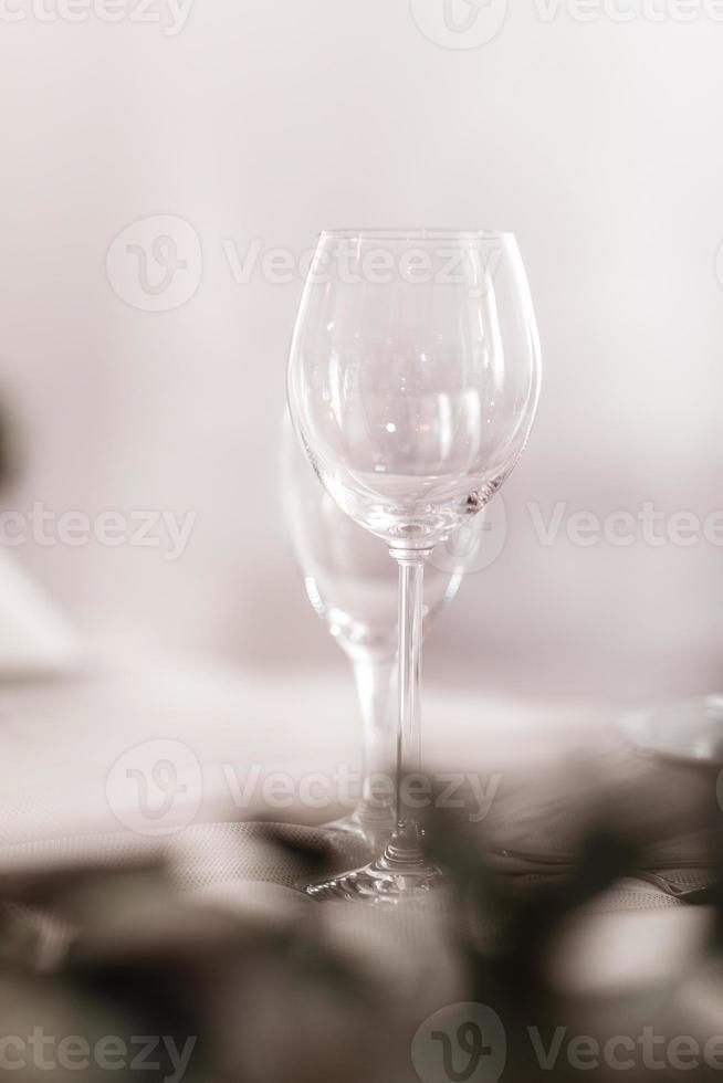 verre vide situé dans le restaurant. mariage, décoration, fête, concept de vacances - table romantique avec nappe blanche, assiettes, verres en cristal photo
