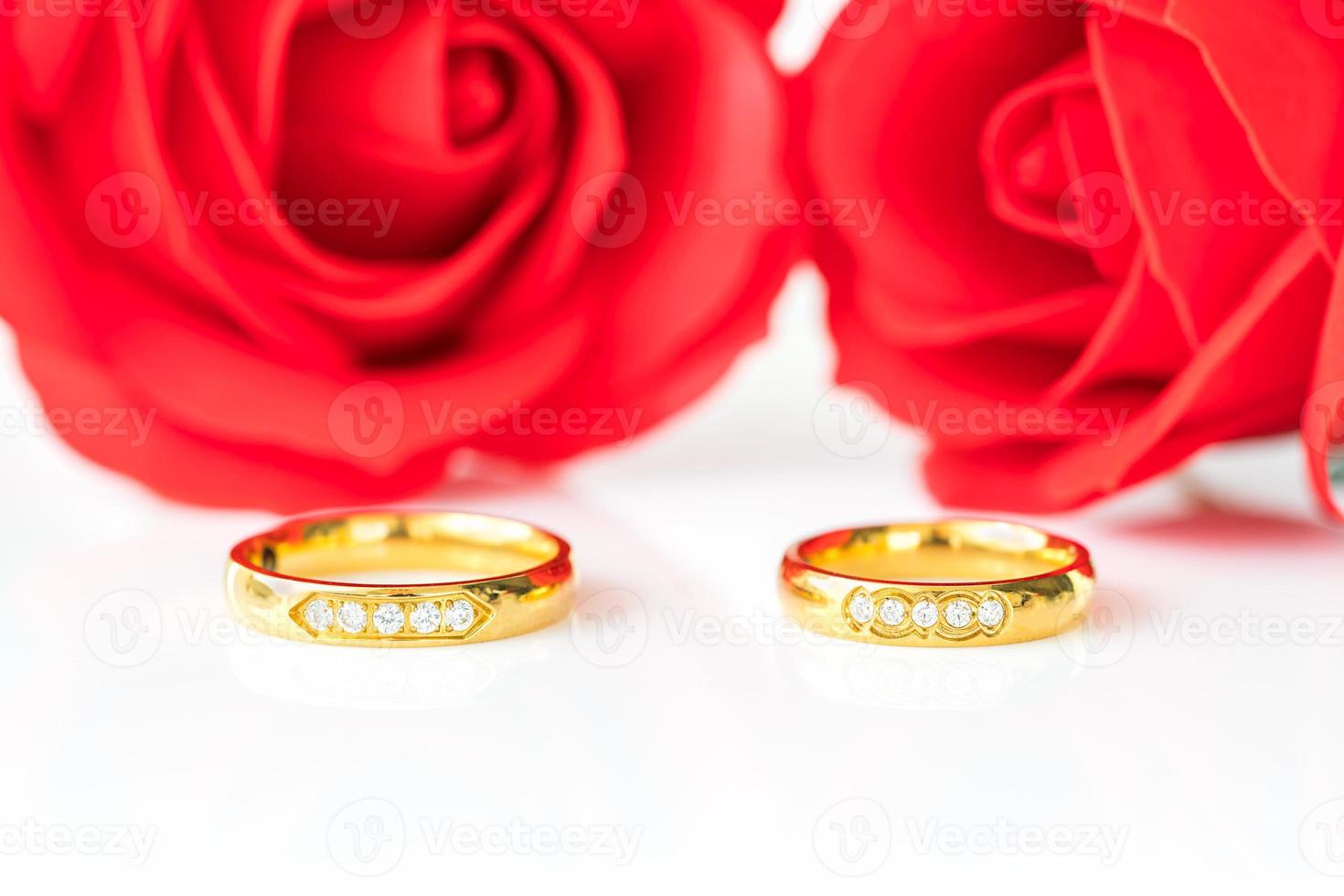 Close up roses rouges et anneaux d'or sur blanc photo