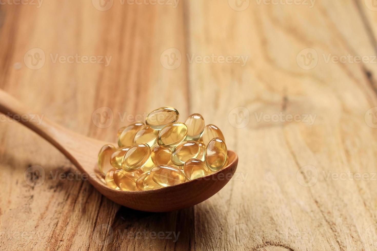 capsules d'huile de poisson sur une cuillère en bois. photo