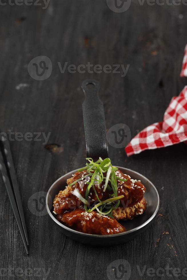 poulet frit coréen ou dakgangjeong. Aile de pilons de poulet frite épicée frite avec sauce épicée rouge photo