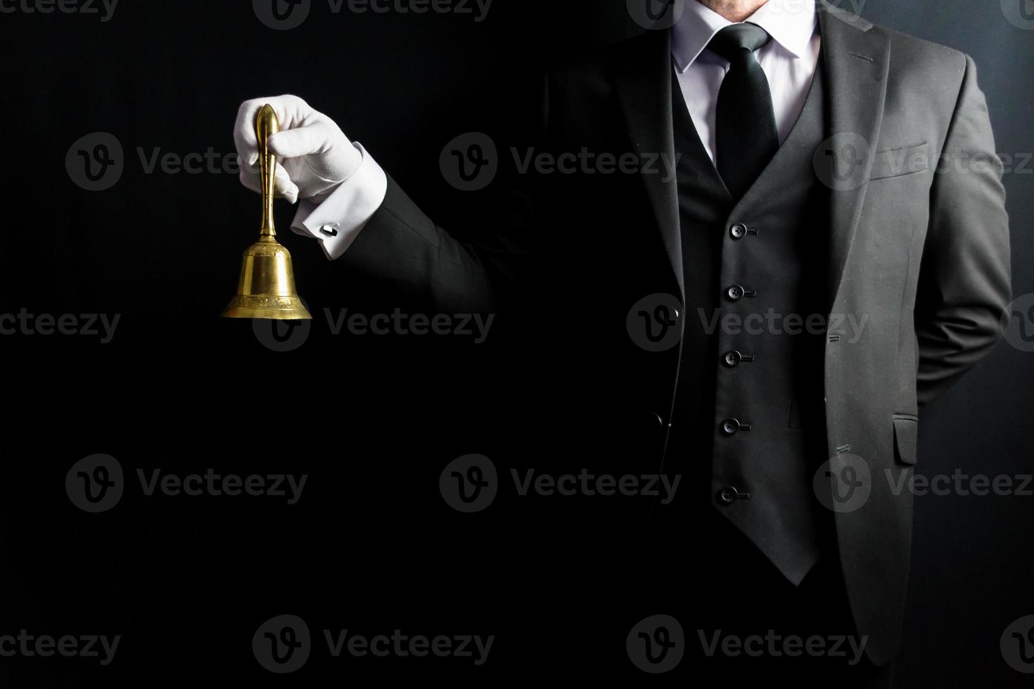 portrait de majordome en costume sombre et gants blancs tenant une cloche en laiton. concept d'industrie de services et d'hospitalité professionnelle. photo