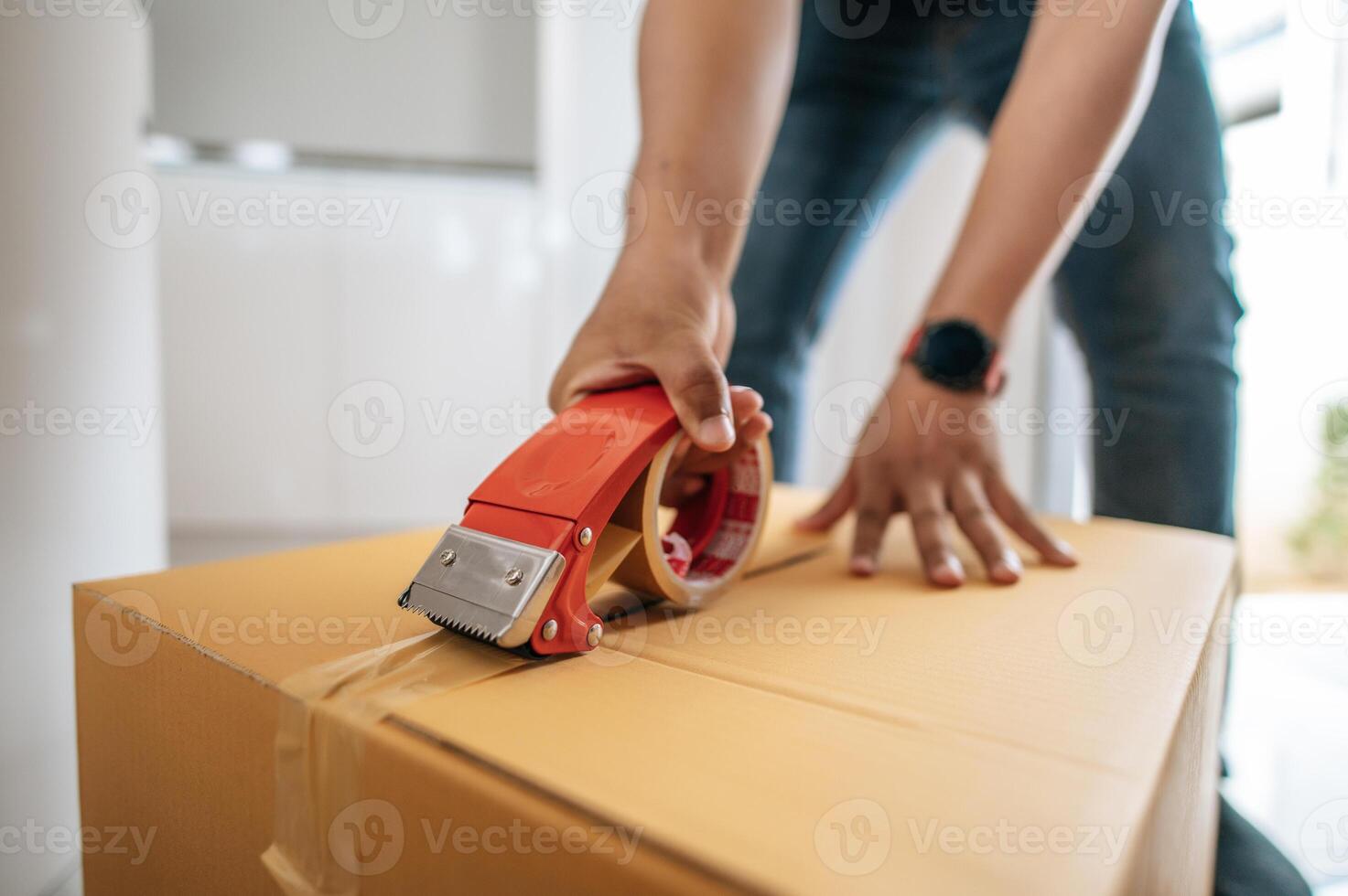 main masculine scellant une grande boîte avec du ruban adhésif pour l'emballage photo