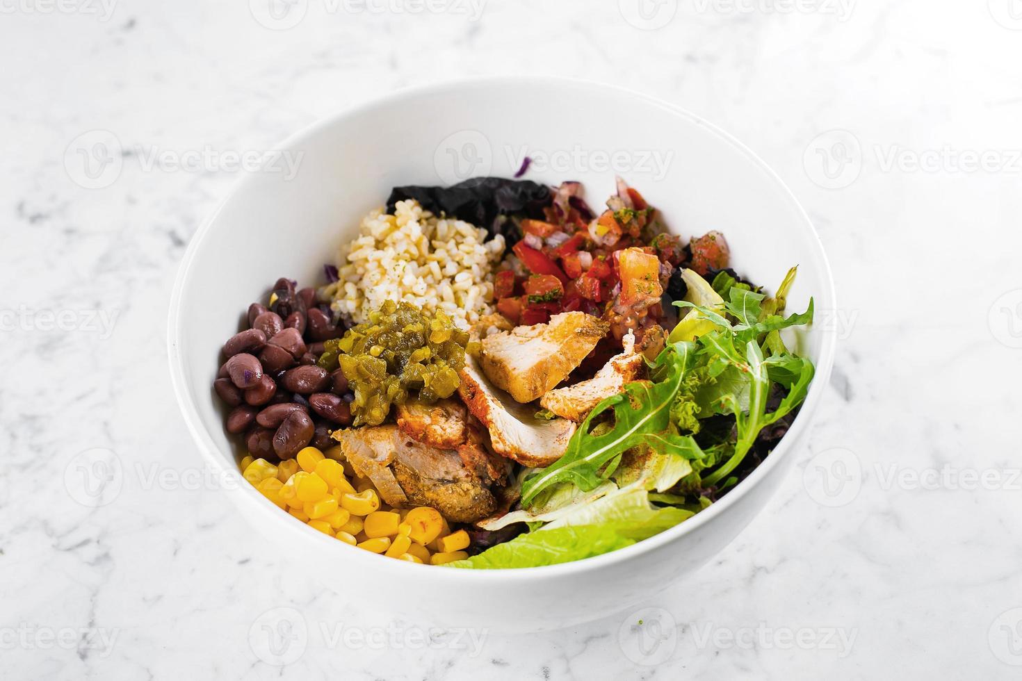 bol de déjeuner mexicain sur fond de marbre. saladier au maïs, haricots rouges, tomate à l'oignon rouge, jalapenios, poitrine de poulet. vue de dessus photo