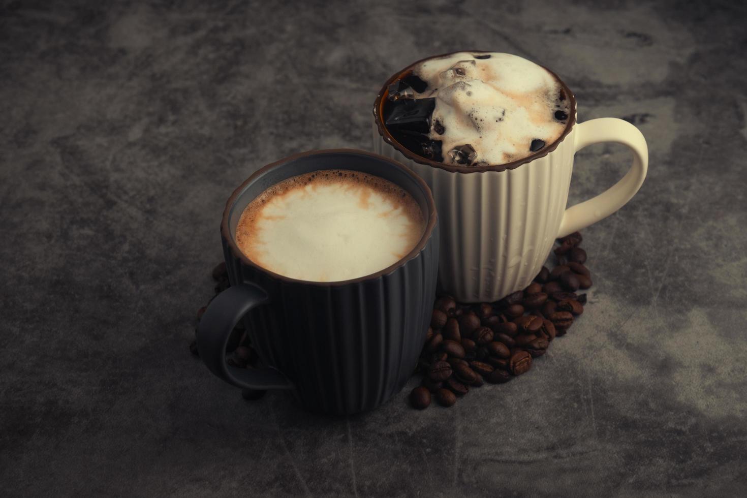 latte chaud et latte glacé avec des grains de café sur fond de béton. photo