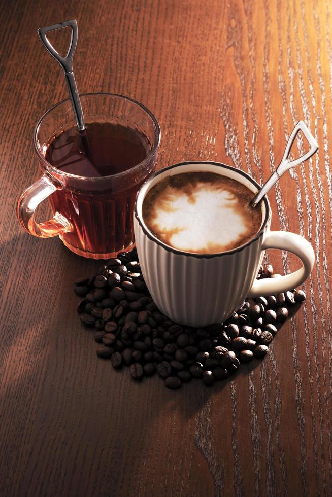 café chaud avec des grains de café et du thé chaud sur fond en bois. photo