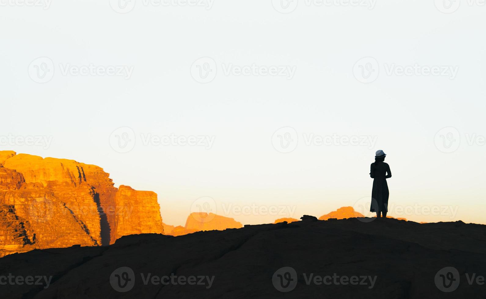 silhouette de femme touristique sur la falaise salue le lever du soleil en jordanie désert de wadi rum photo
