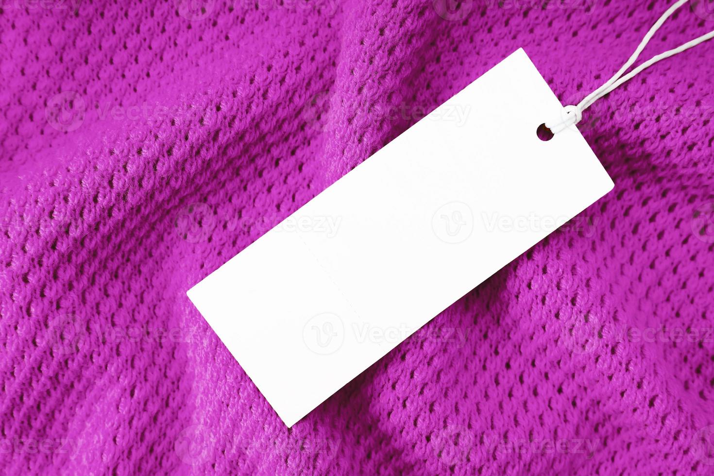 étiquette de vêtement rectangulaire blanche sur fond de tissu tricoté violet. shopping, vente, maquette de remise photo