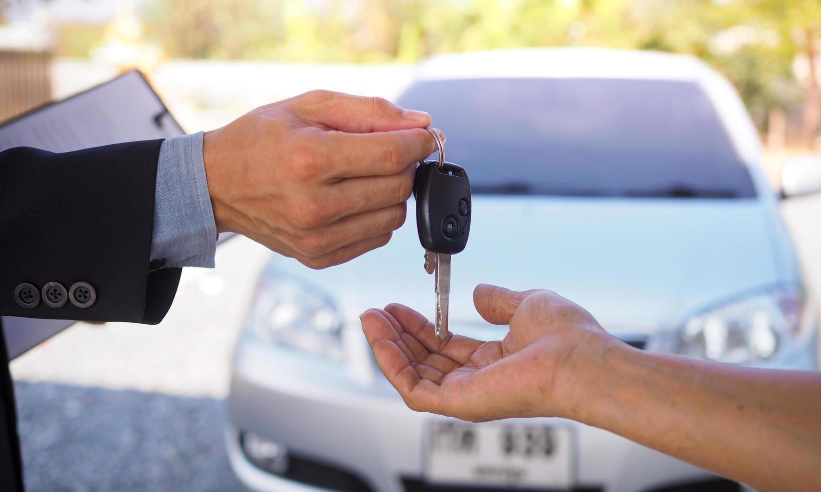 le vendeur remet les clés à un nouvel acquéreur. entreprise automobile, vente de voitures, transaction, concept de geste et de personnes - gros plan du concessionnaire donnant la clé. photo