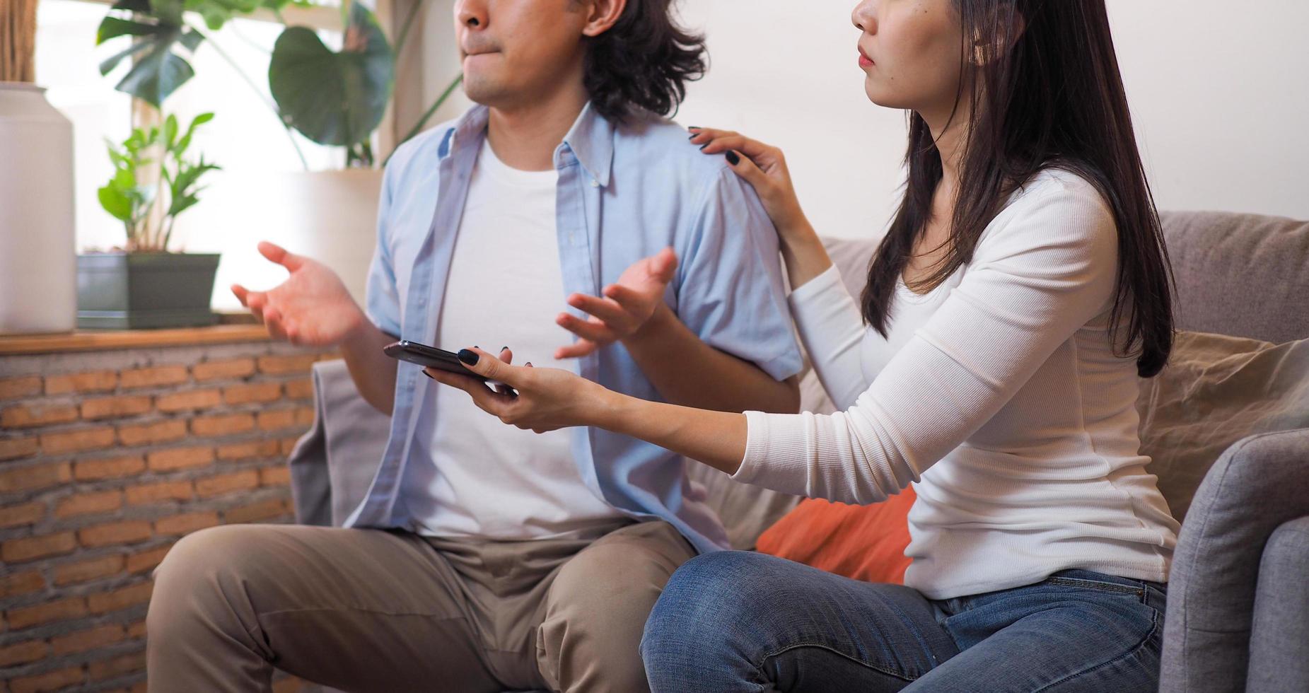 la femme avait besoin d'une explication sur l'histoire indigne de confiance sur le téléphone personnel de son mari assis sur le canapé du salon dans la maison. ne fais pas confiance photo